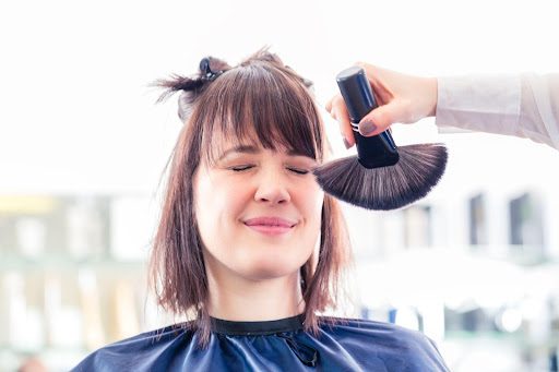 A hairdresser brushes hair off a customer’s face.