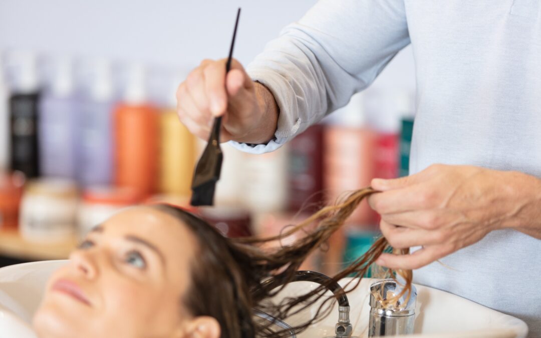 A stylist applying a solution to another woman’s hair